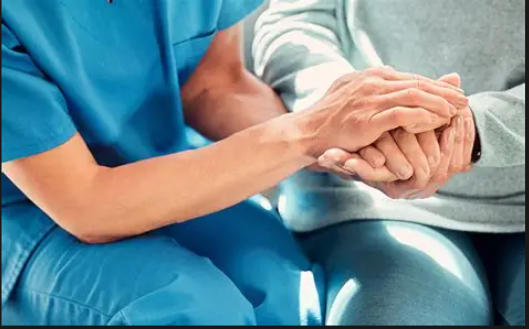 Operatrice che tiene tra le mani la mano di una persona anziana